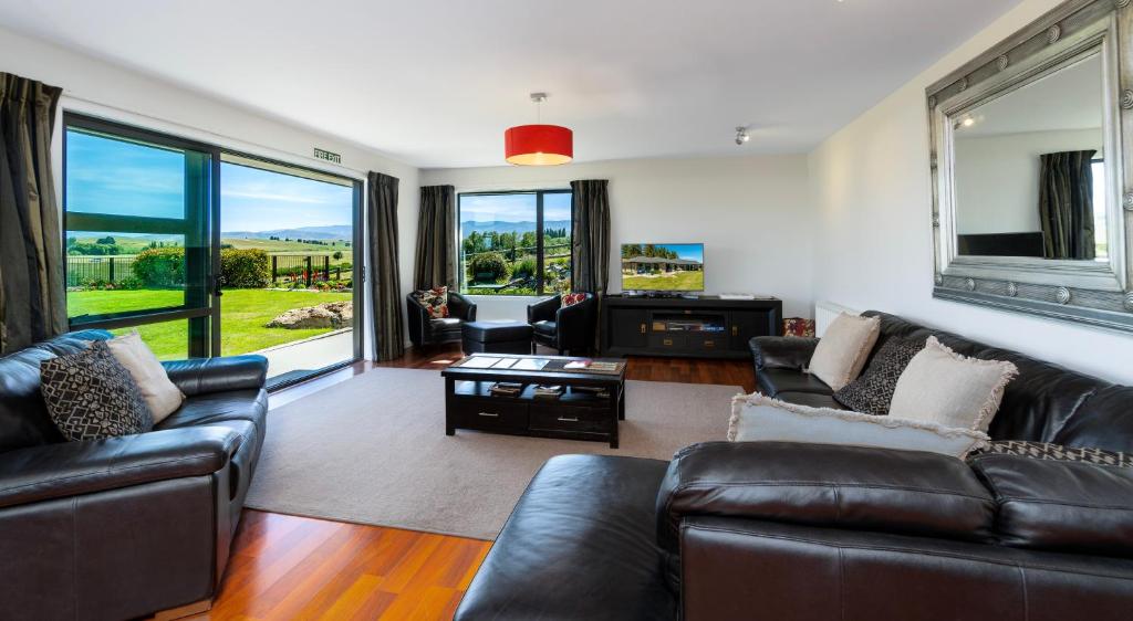 a living room with leather furniture and a large window at Inverlair Lodge in Oturehua