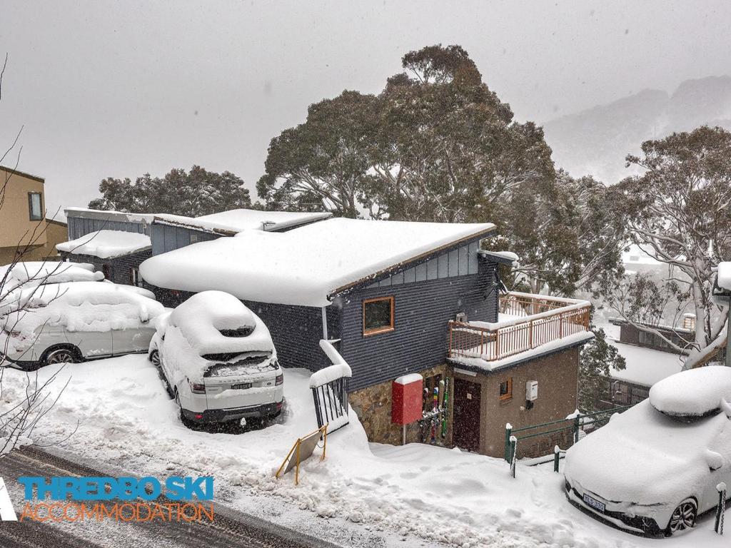 a house covered in snow with cars parked outside at Golden Eagle 1 in Thredbo