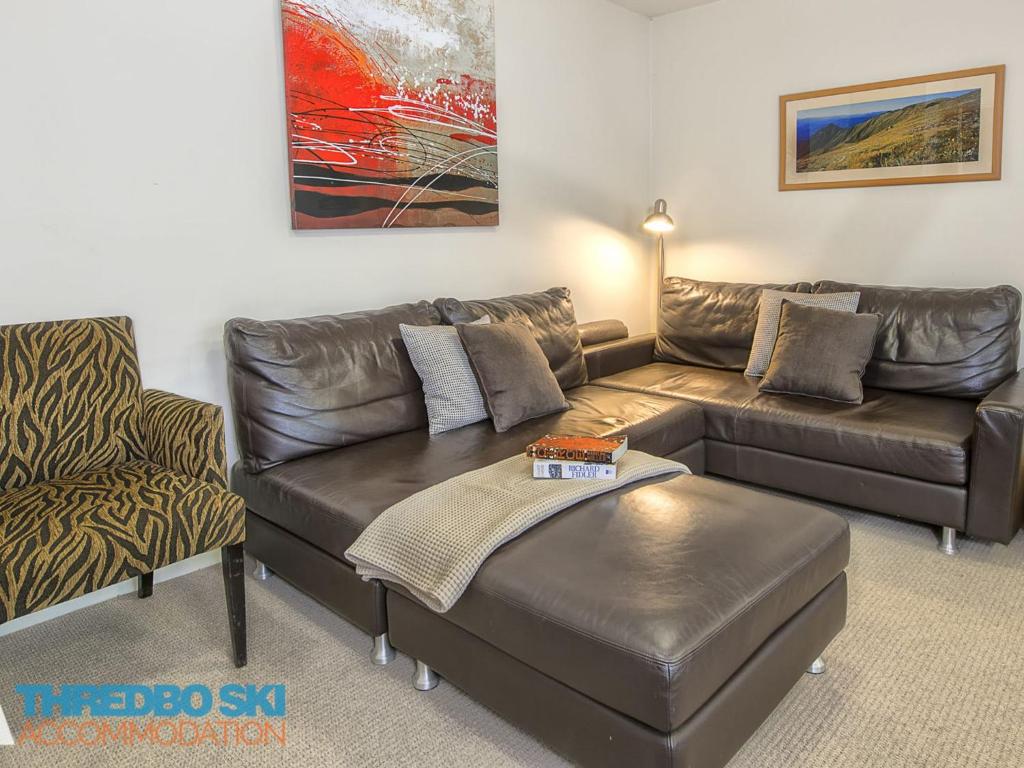 a living room with a leather couch and a chair at Golden Eagle 1 in Thredbo