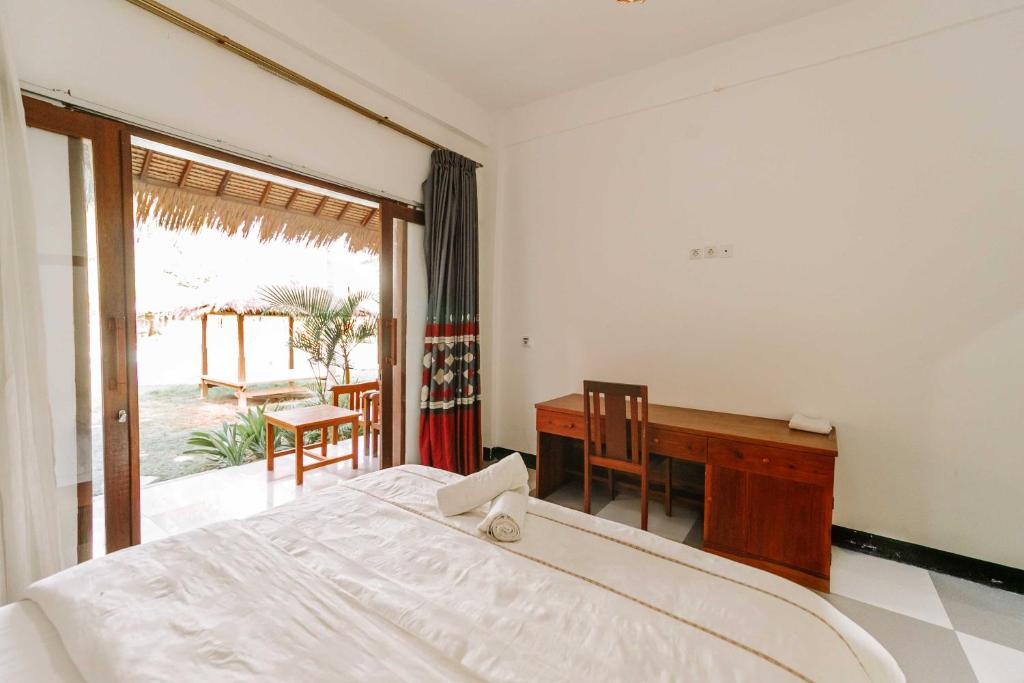 a bedroom with a bed and a desk and a window at Dream CoWork Hotel in Kuta Lombok