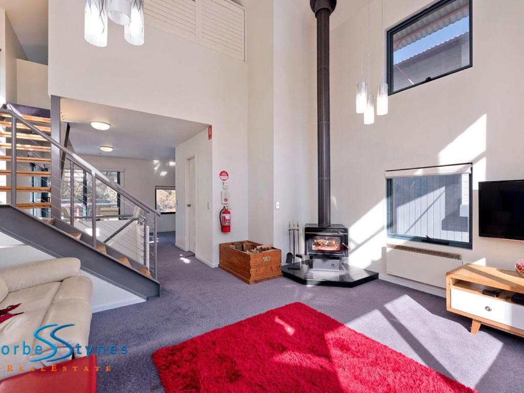 a living room with a fireplace and a red rug at Talgara 2 in Thredbo