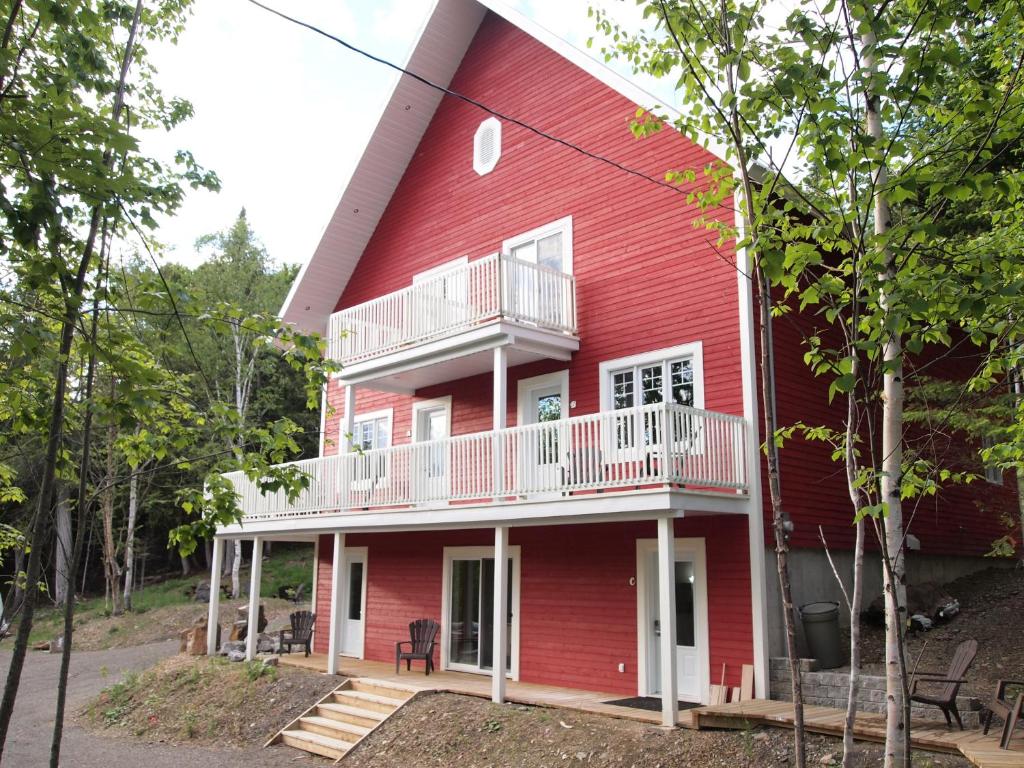 a red house with white railings on the side of it at Chalet Rouge in New Richmond