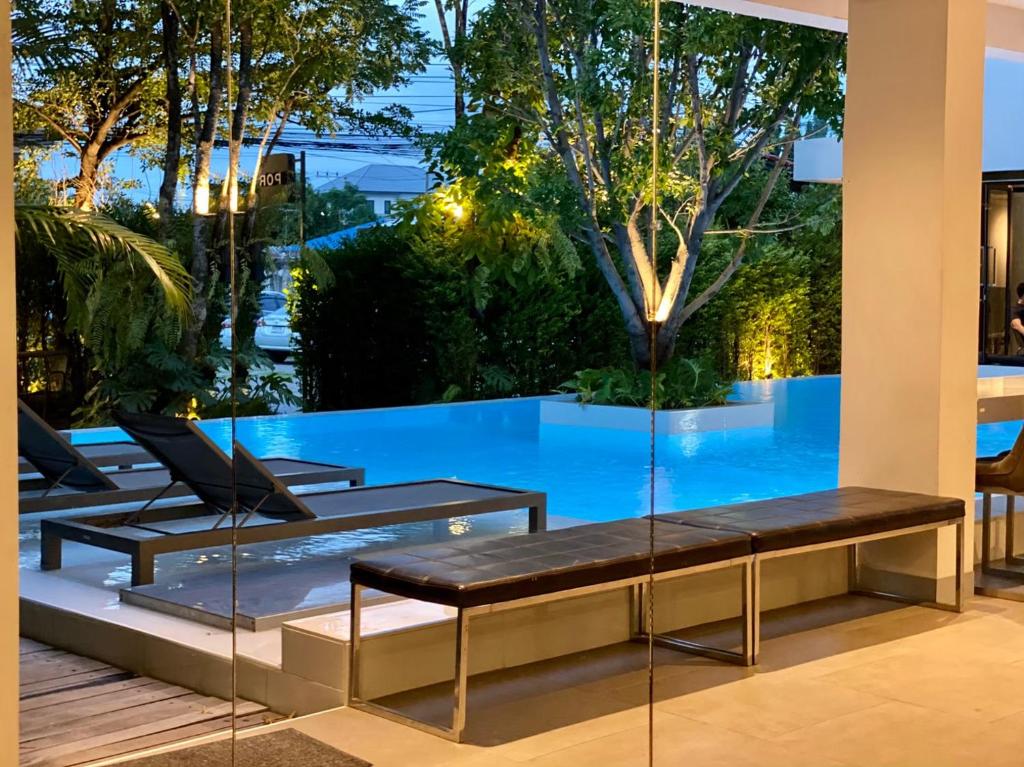 A dusk-lit pool terrace combines loungers, benches and leafy garden views.