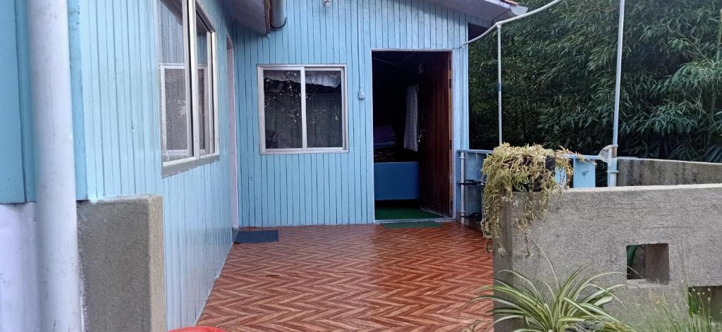 ein blaues Gebäude mit einer Tür und einer Veranda in der Unterkunft Joe's Farm in Darjeeling
