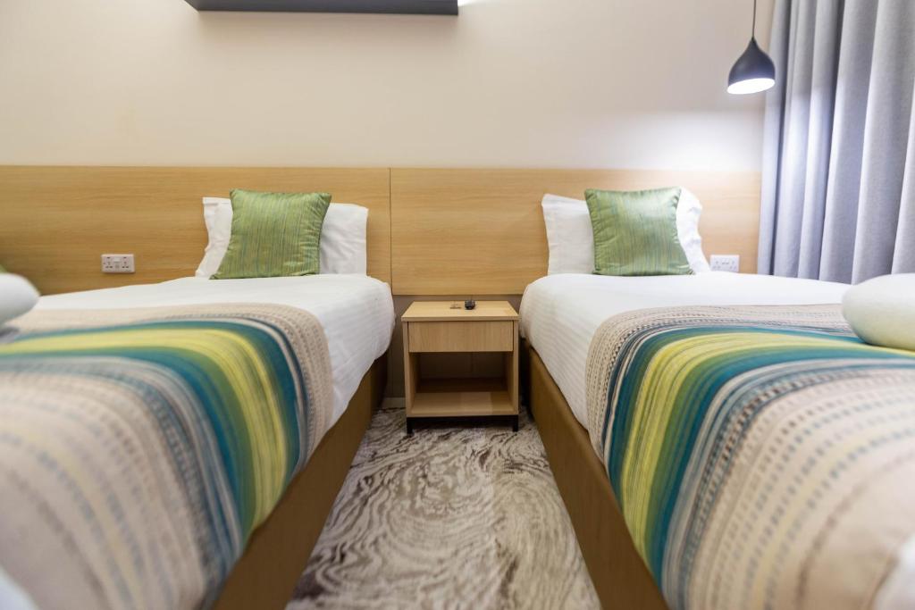 two beds sitting next to each other in a room at Kozi Suites Nairobi Airport in Nairobi