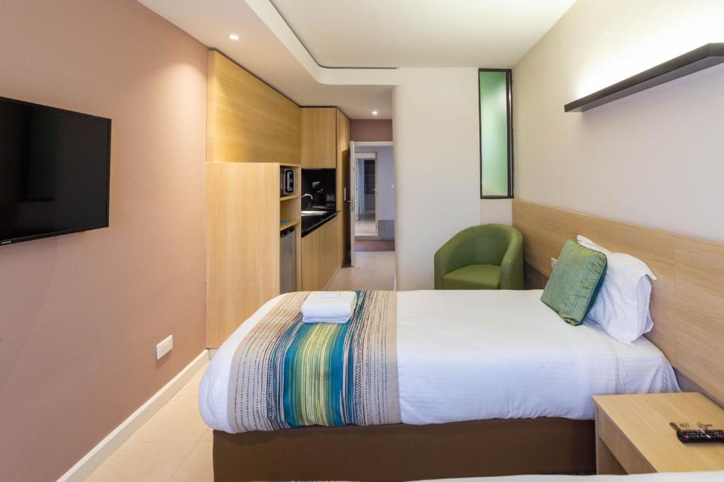 a hotel room with a bed and a television at Kozi Suites Nairobi Airport in Nairobi