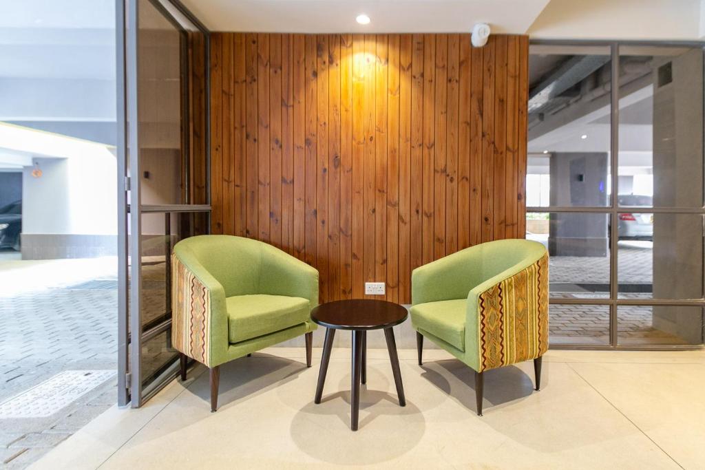 two green chairs and a table in a lobby at Kozi Suites Nairobi Airport in Nairobi