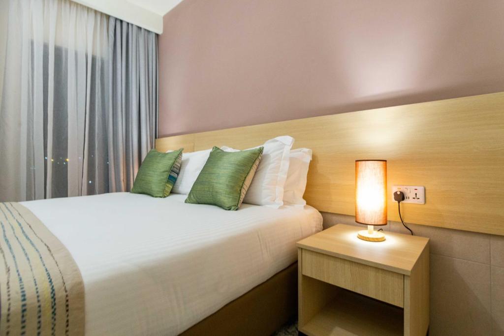 a bedroom with a bed with a lamp on a table at Kozi Suites Nairobi Airport in Nairobi