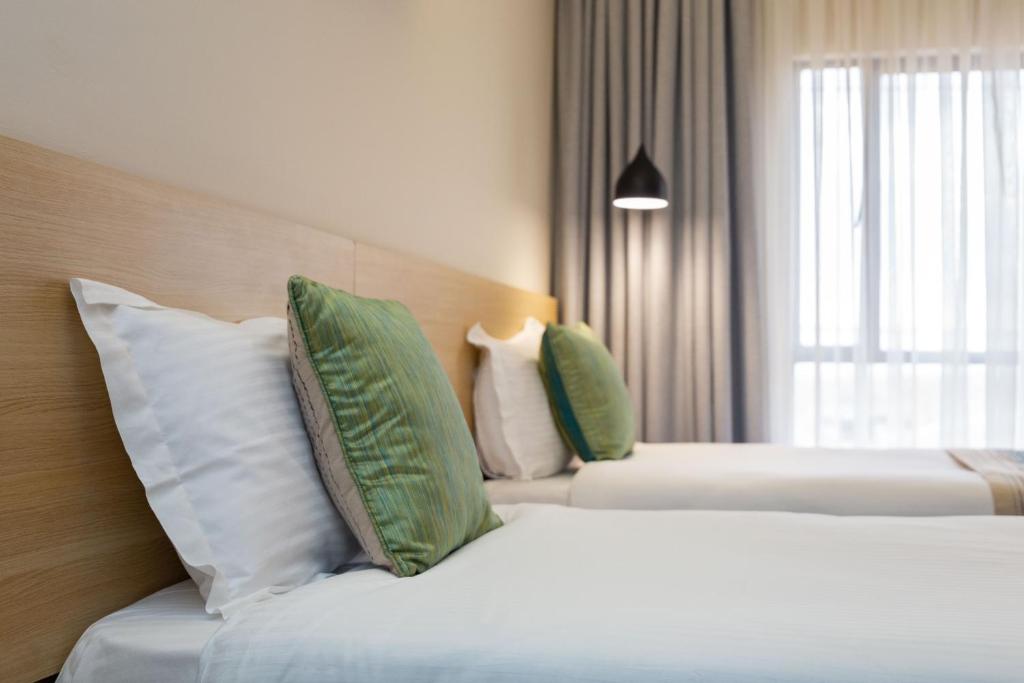 a hotel room with two beds with green and white pillows at Kozi Suites Nairobi Airport in Nairobi