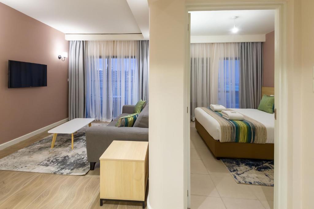 a bedroom with a bed and a living room at Kozi Suites Nairobi Airport in Nairobi