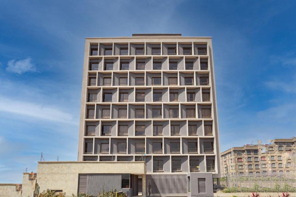 a tall building with many windows on it at Kozi Suites Nairobi Airport in Nairobi