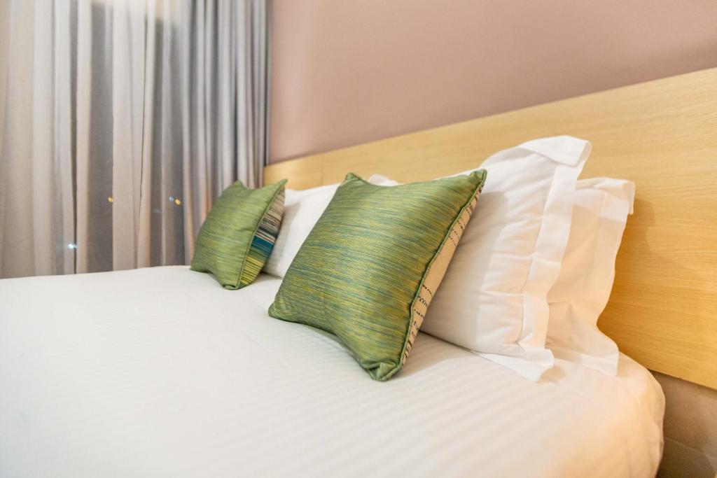 a bed with two pillows on top of it at Kozi Suites Nairobi Airport in Nairobi