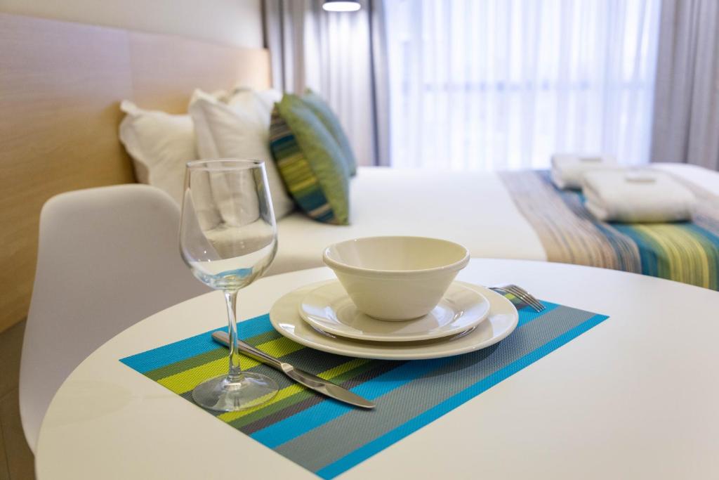a table with a plate and a glass of wine at Kozi Suites Nairobi Airport in Nairobi