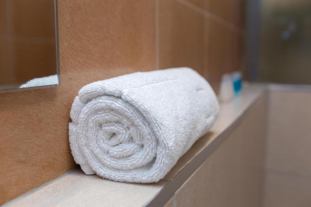a roll of white towels sitting on a counter in a bathroom at Kozi Suites Nairobi Airport in Nairobi