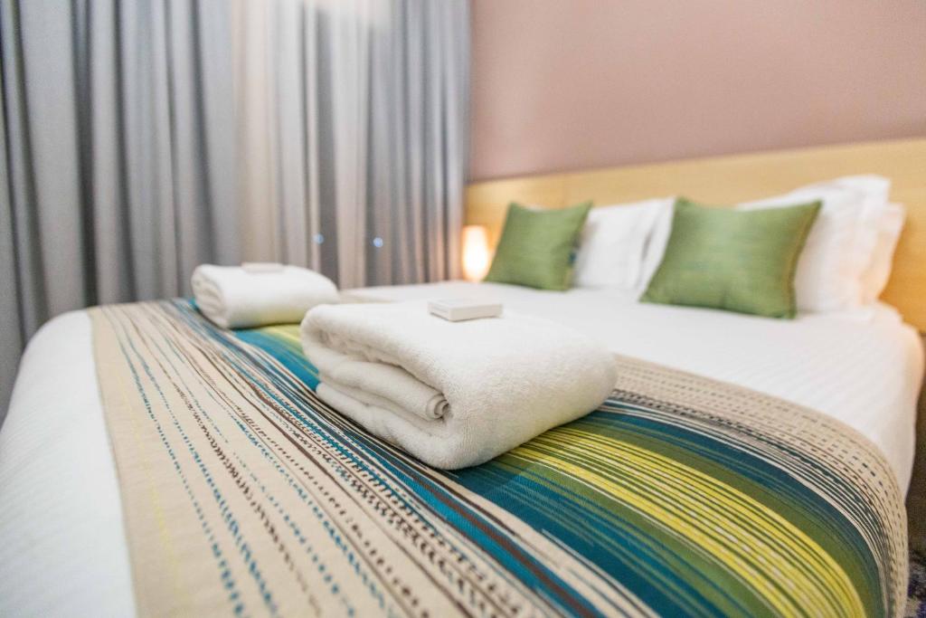 a bedroom with a bed with white blankets and pillows at Kozi Suites Nairobi Airport in Nairobi