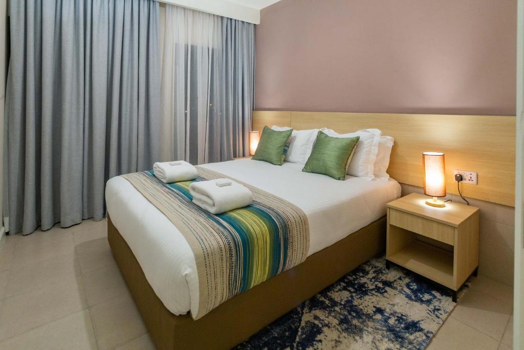 a bedroom with a bed with two towels on it at Kozi Suites Nairobi Airport in Nairobi