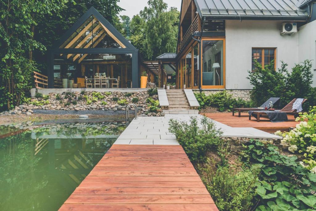 uma casa com um passadiço de madeira ao lado de um lago em Chata nad Wąwozem em Nałęczów