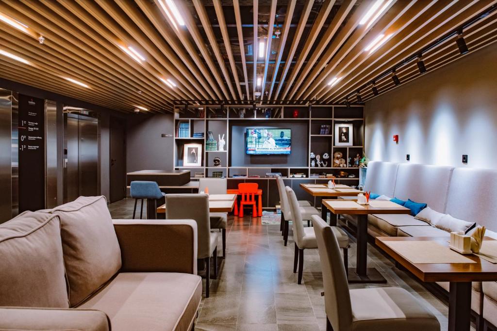 a dining room with tables and chairs and a tv at Maxima Domodedovo Hotel in Domodedovo