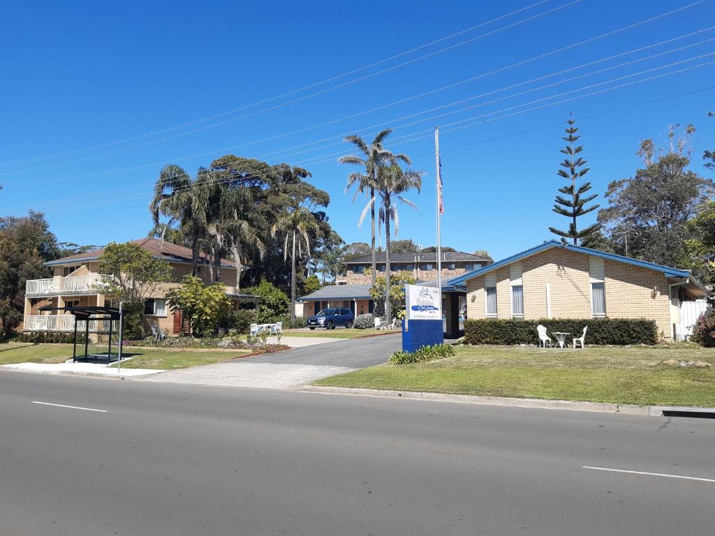 a street view of a house with palm trees at Dolphins of Mollymook Motel and Fifth Green Apartments in Mollymook