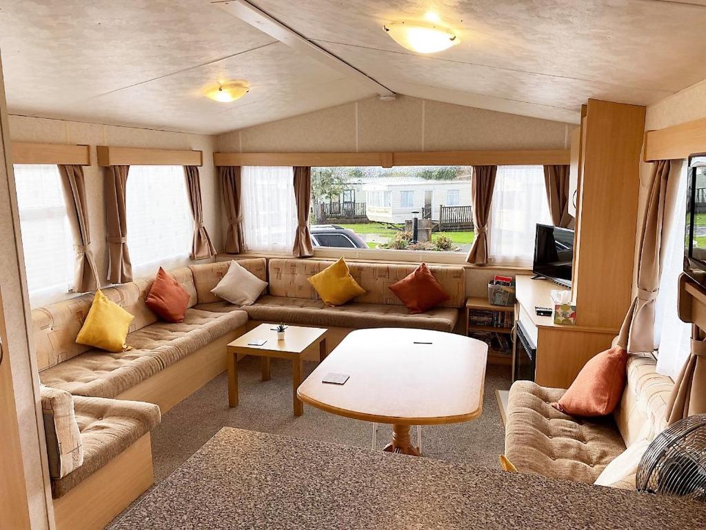 a living room with a couch and a table at Devon Barnstaple Self Catering Tarka Holiday Park Free Wi-Fi Spacious Static Caravan sleeps 4 Pets allowed location Devon EX31 4AU Just 6 miles from Saunton Sands Please note no sign written vehicles are allowed to park on the holiday park overnight in Barnstaple