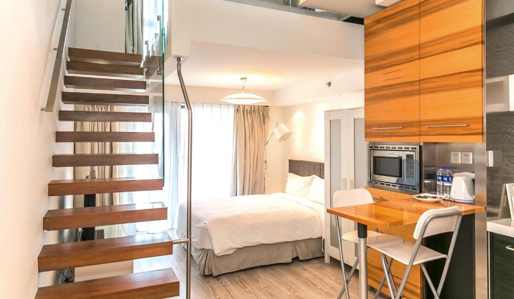 ein Schlafzimmer mit einem Bett, einem Schreibtisch und einer Treppe in der Unterkunft Modena by Fraser Putuo Shanghai in Shanghai