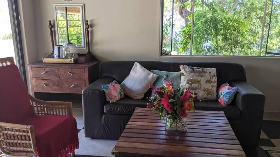 a living room with a couch with pillows and a table at Sunbirds Cottage in Kasane