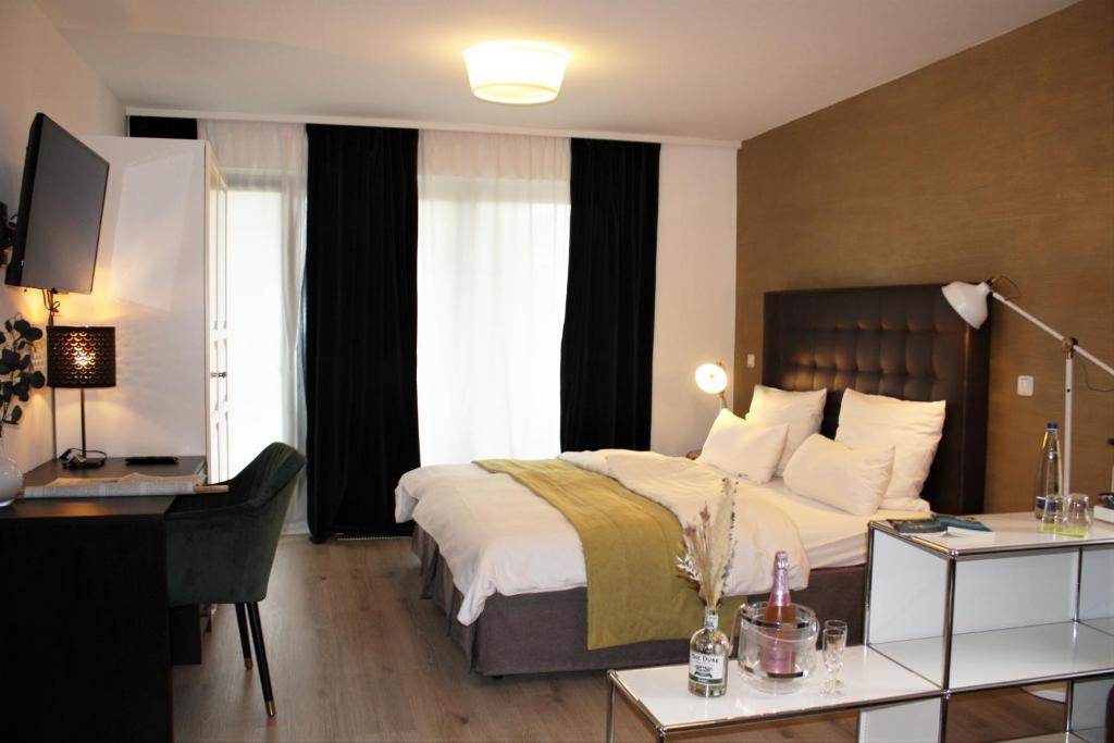 ein Hotelzimmer mit einem großen Bett und einem Schreibtisch in der Unterkunft Hotel zum See garni in Dießen am Ammersee