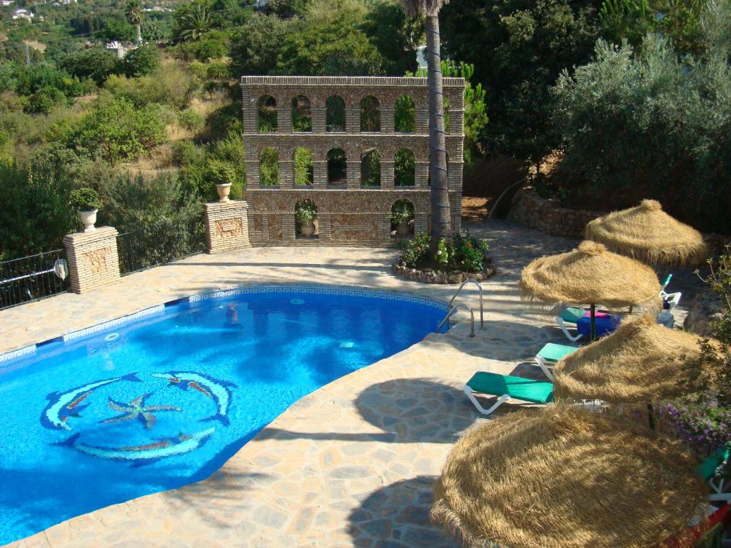 una piscina con sombrillas y sillas y un edificio en Tu Villa Rural Almendro 3 Dormitorios, en Alhaurín el Grande