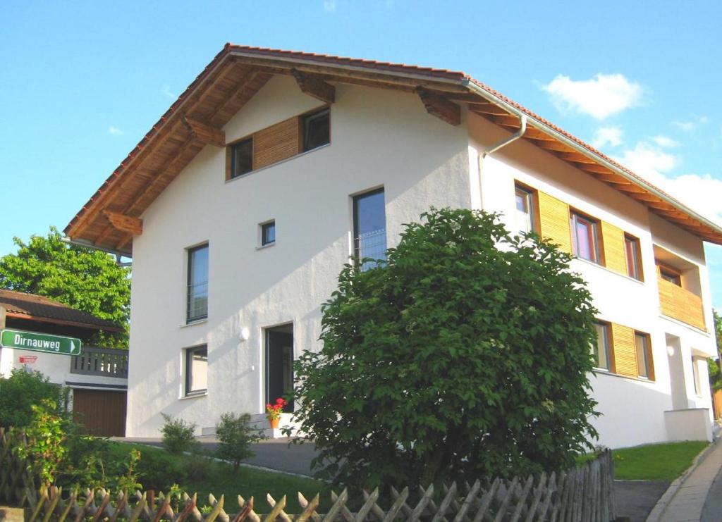 Una casa blanca con un árbol delante. en Wohlfühl-Ferienwohnung Sonja, en Bodenmais