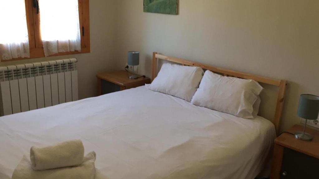 1 dormitorio con 1 cama con sábanas y almohadas blancas en Apartamento Central, en Alp