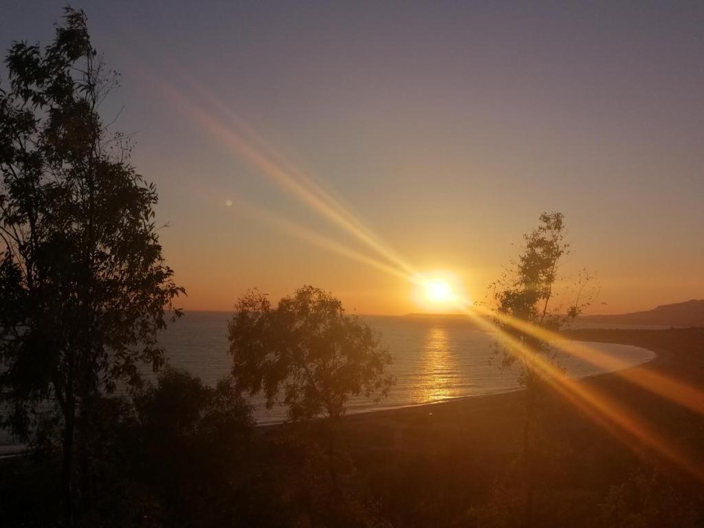 una puesta de sol sobre un cuerpo de agua con árboles en Villa Sole Mare, en Seccagrande