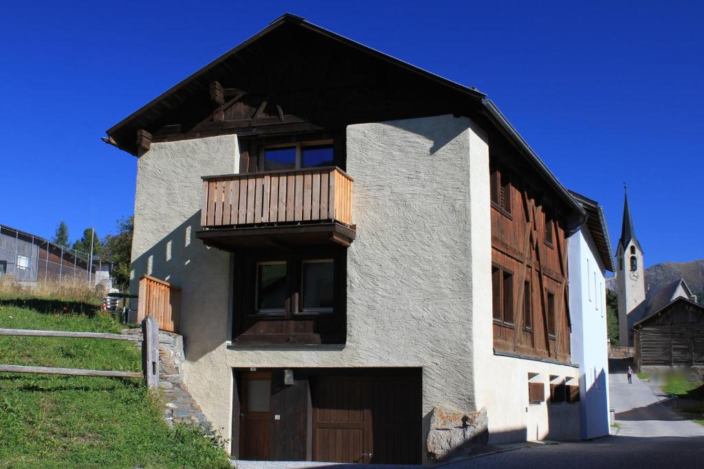 a house with a balcony and a church at Chasa Tablà Guarda in Guarda