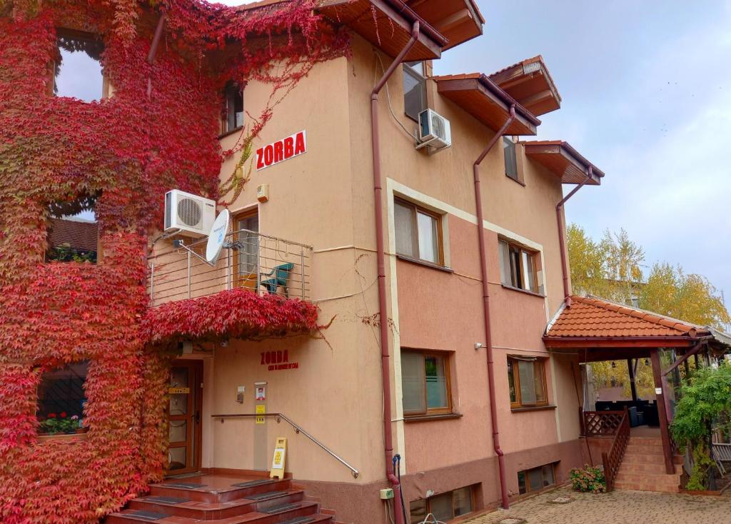 Un edificio con un'edera rossa sul lato. di Villa Zorba a Bucarest