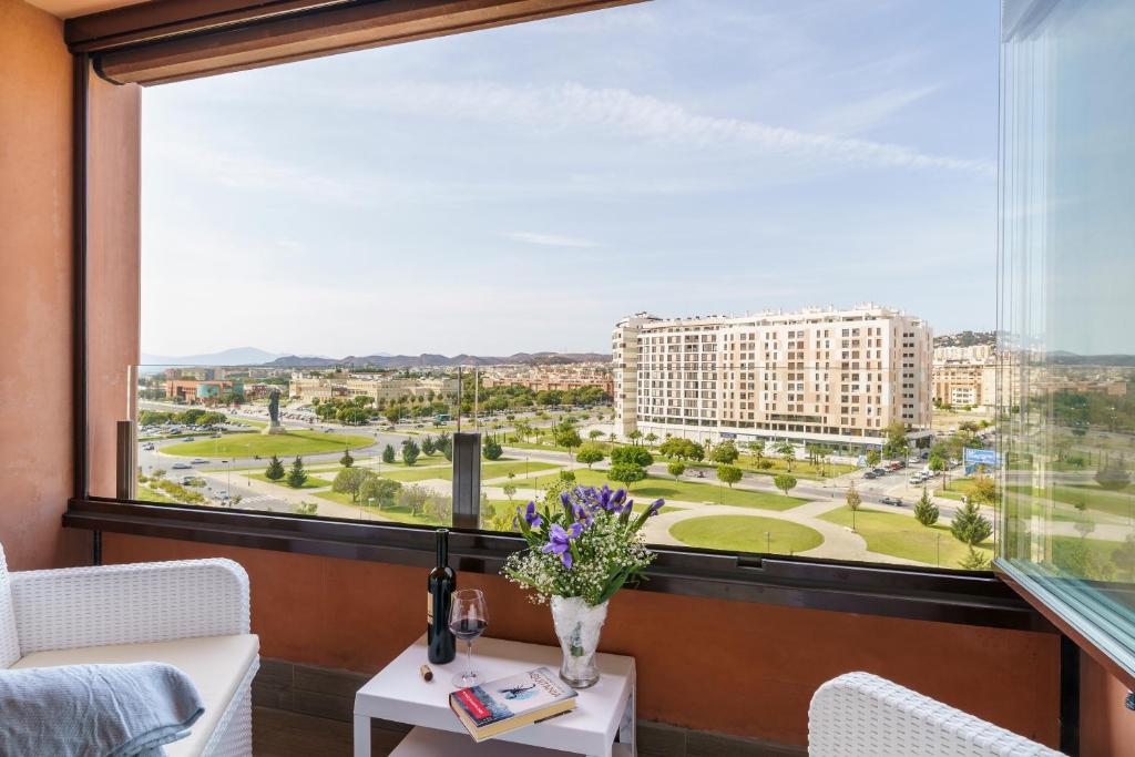 a room with a large window and a table with flowers at Teatinos Sky Garden I - CT 164 in Málaga