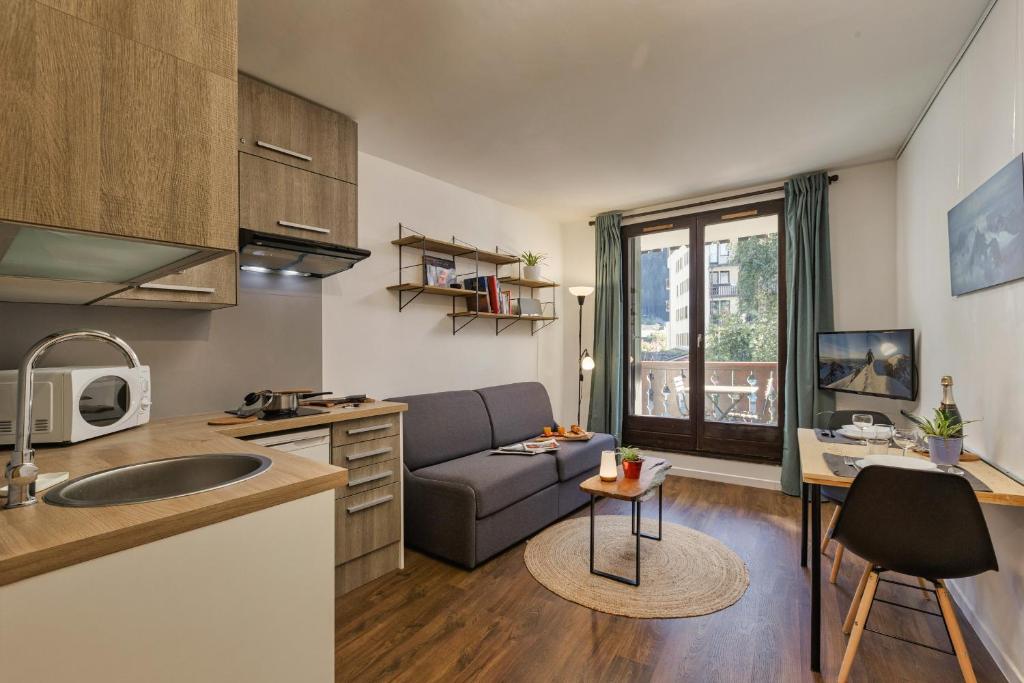een keuken en een woonkamer met een bank en een tafel bij Chamonix Sud - Bâtiment Iris 164 - Happy Rentals in Chamonix-Mont-Blanc