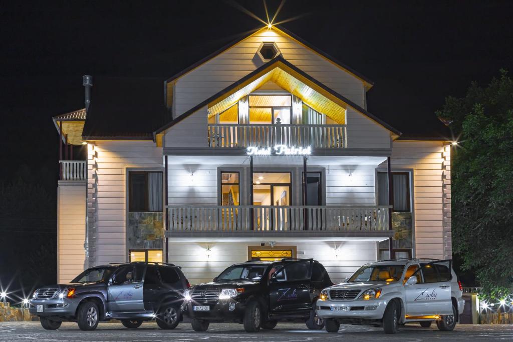 three trucks parked in front of a house at night at Hotel Patriot in Mestia