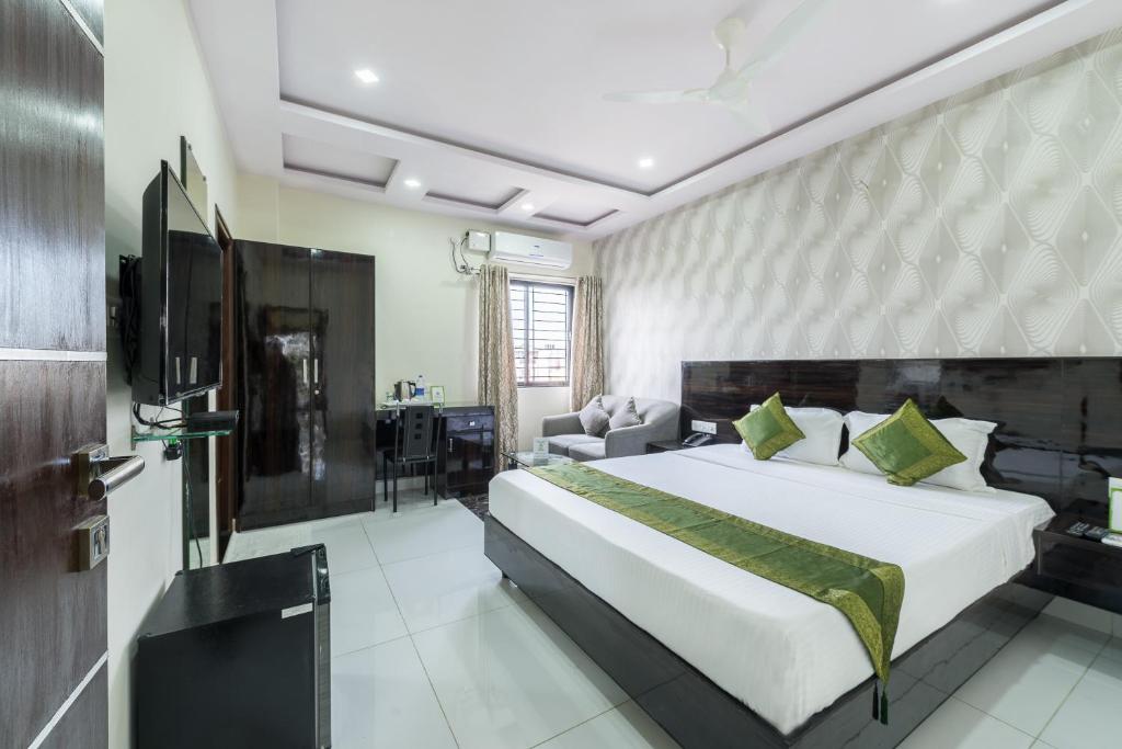 a bedroom with a large bed and a couch at Treebo Greenwood Premier Suites, Old Airport Road in Bengaluru
