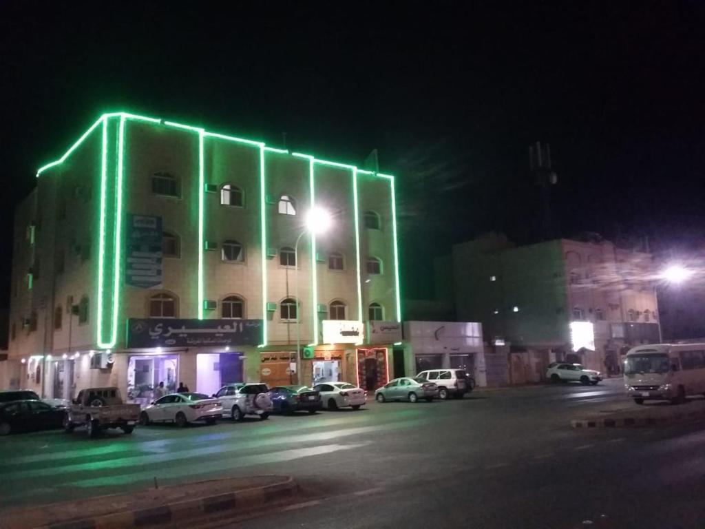 a building with green lights on the side of it at العييري للشقق المفروشة حائل 4 in Hail