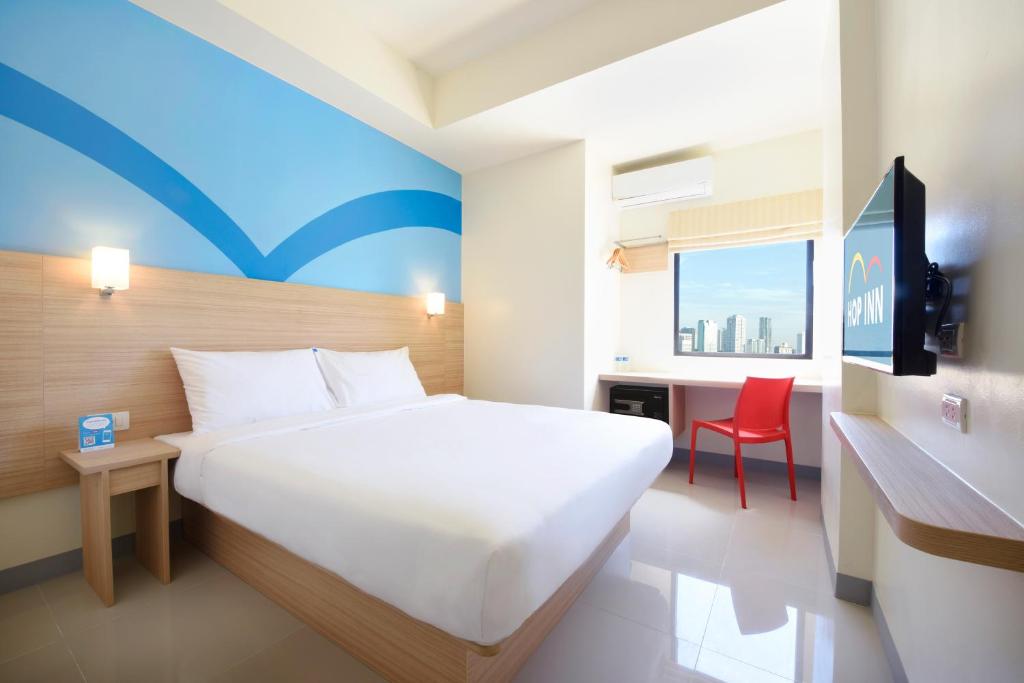 a bedroom with a large white bed and a red chair at Hop Inn Ortigas Center Manila in Manila