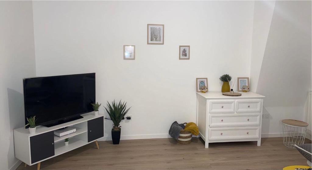 a living room with a television and a white dresser at Petit cocon proche gare et commerces in Chantilly