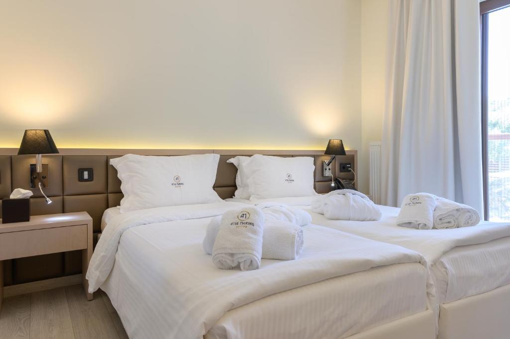 two beds in a hotel room with towels on them at Ayia Marina Suites in Ouranoupoli