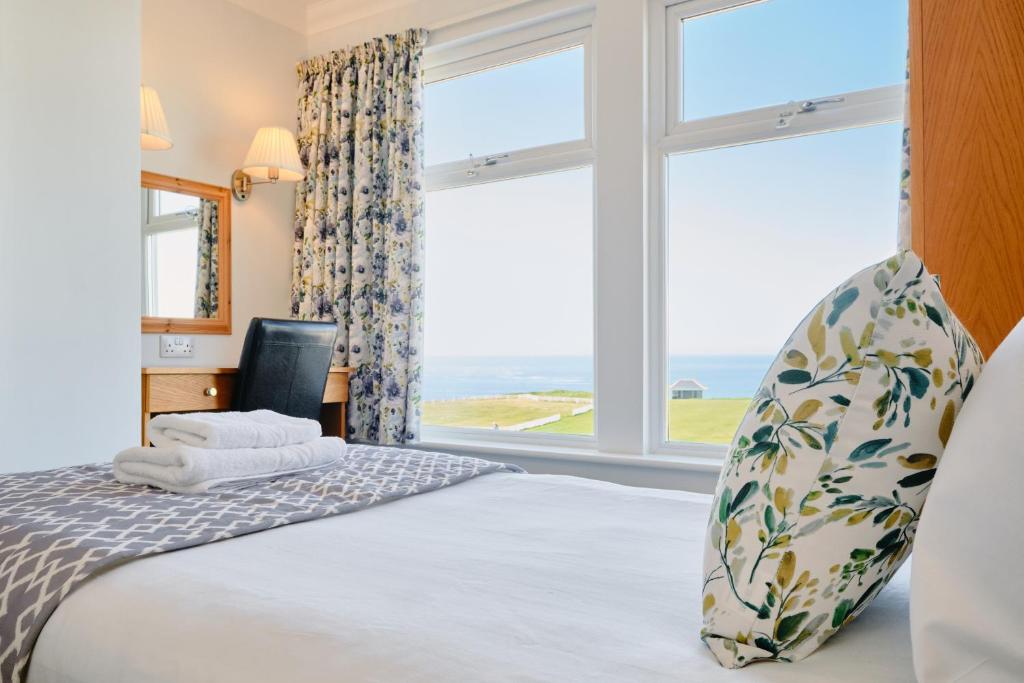 a bedroom with a bed and a large window at The Kilbirnie Hotel in Newquay