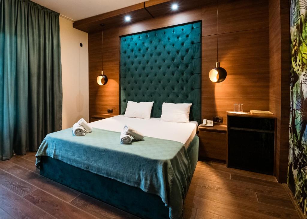 a bedroom with a large bed with a blue headboard at Hotel Zeleni Vir in Niš
