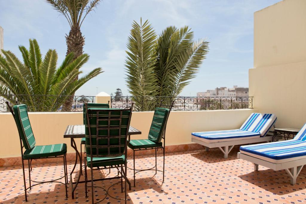 een patio met stoelen, tafels en palmbomen bij Aghata Palms Riad in Essaouira