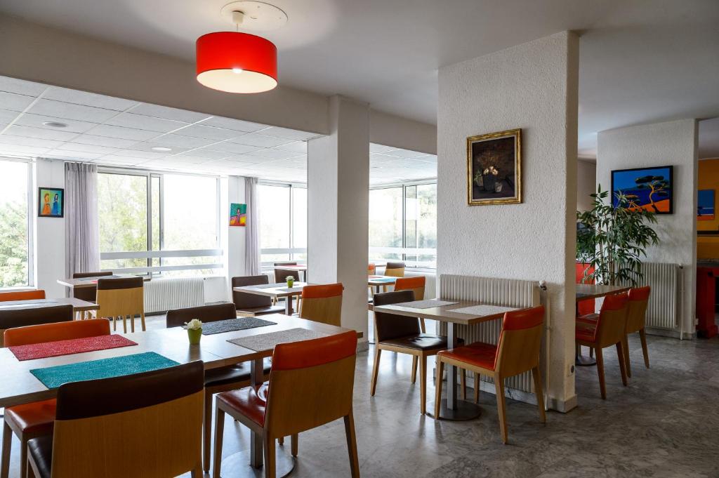 - une salle à manger avec des tables, des chaises et des fenêtres dans l'établissement Hôtel Saint Roch, à Martigues