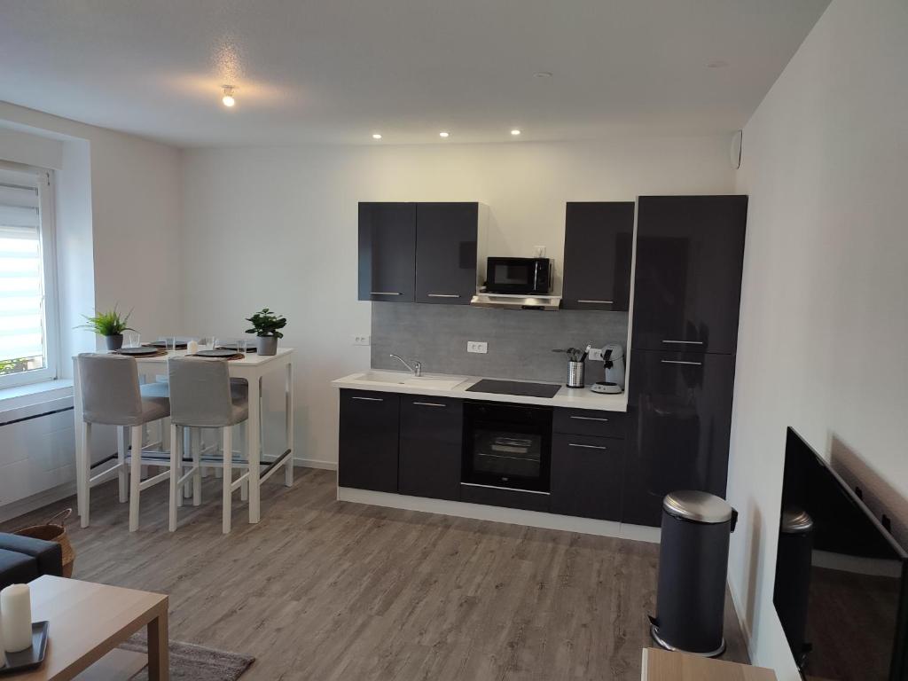 a kitchen with a black refrigerator and a table at *** les loges de la friche DMC *** in Mulhouse