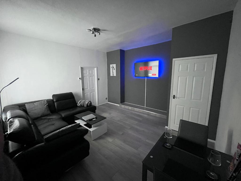 sala de estar con sofá y TV en la pared en The Grey House en Blythe