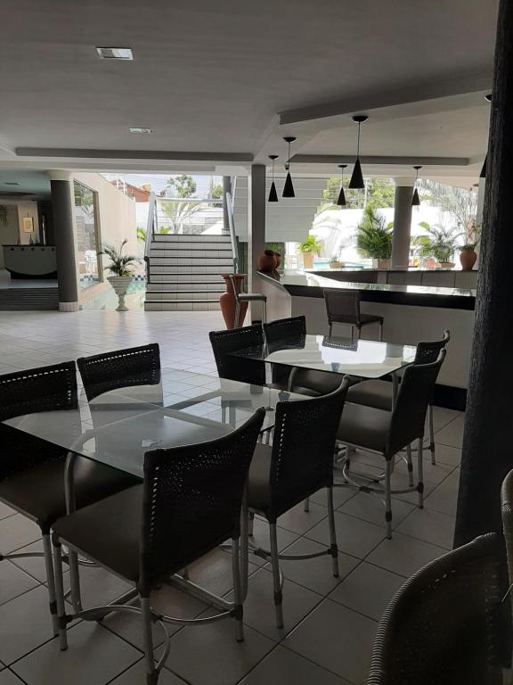 a dining room with tables and chairs and a kitchen at Nautillus Hotel in Parnaíba