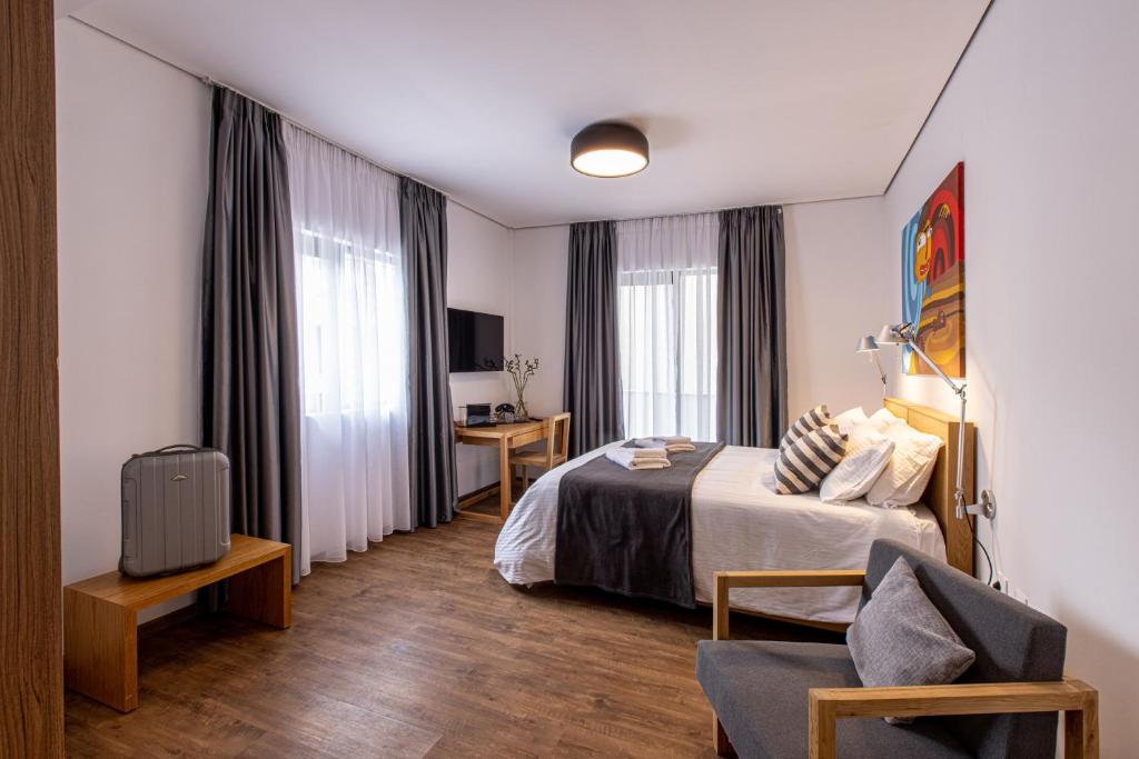 Habitación de hotel con cama y silla en Saint George Hotel Rooms, en Komotiní