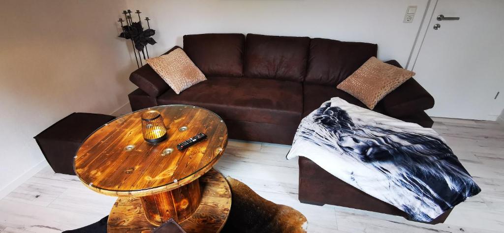 sala de estar con sofá marrón y mesa de madera en Ferienwohnung Alpakahof Goslar, en Goslar